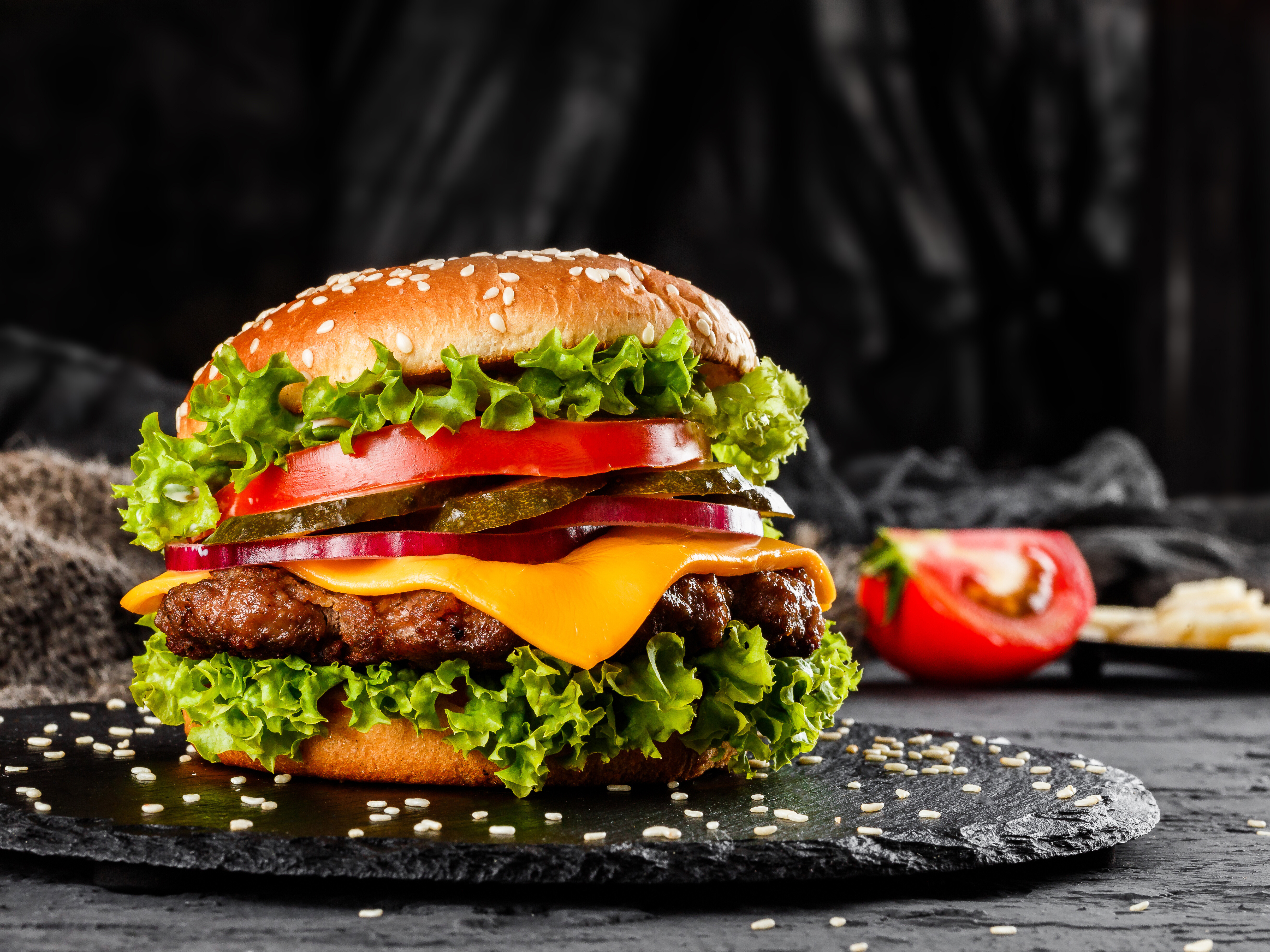 Burger with a patty, tomatoes, cheese, pickles, salad and ketchup