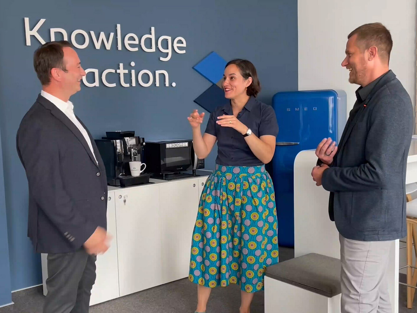 Two man and a woman in business clothing standing in a room